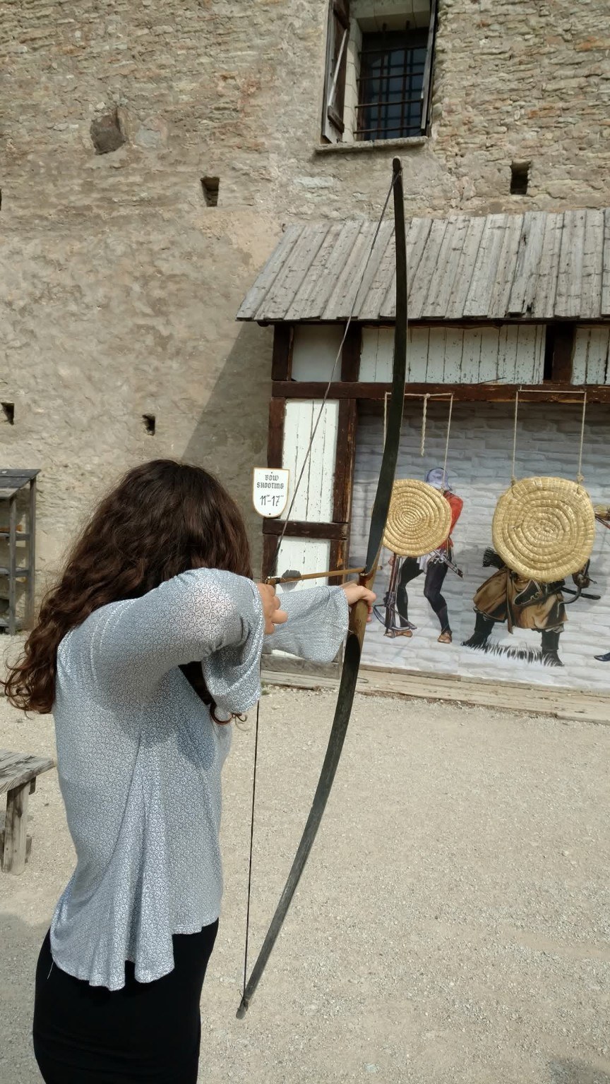 Archery at Rakvere Castle with Paige aiming a bow inside the medieval walls