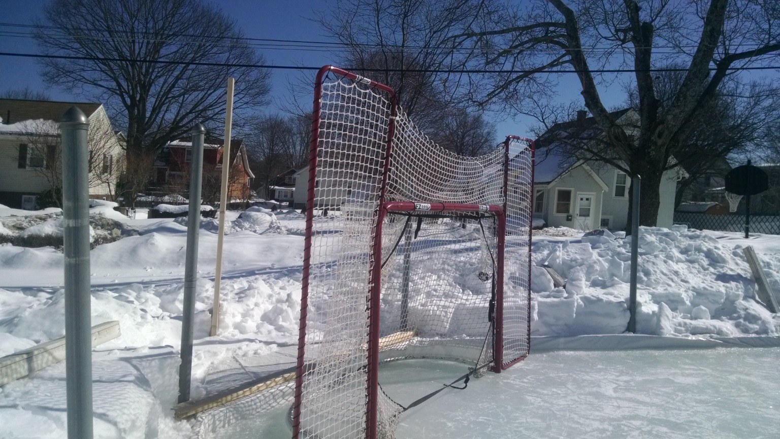 Hockey goal and tall snowbanks around the backyard rink