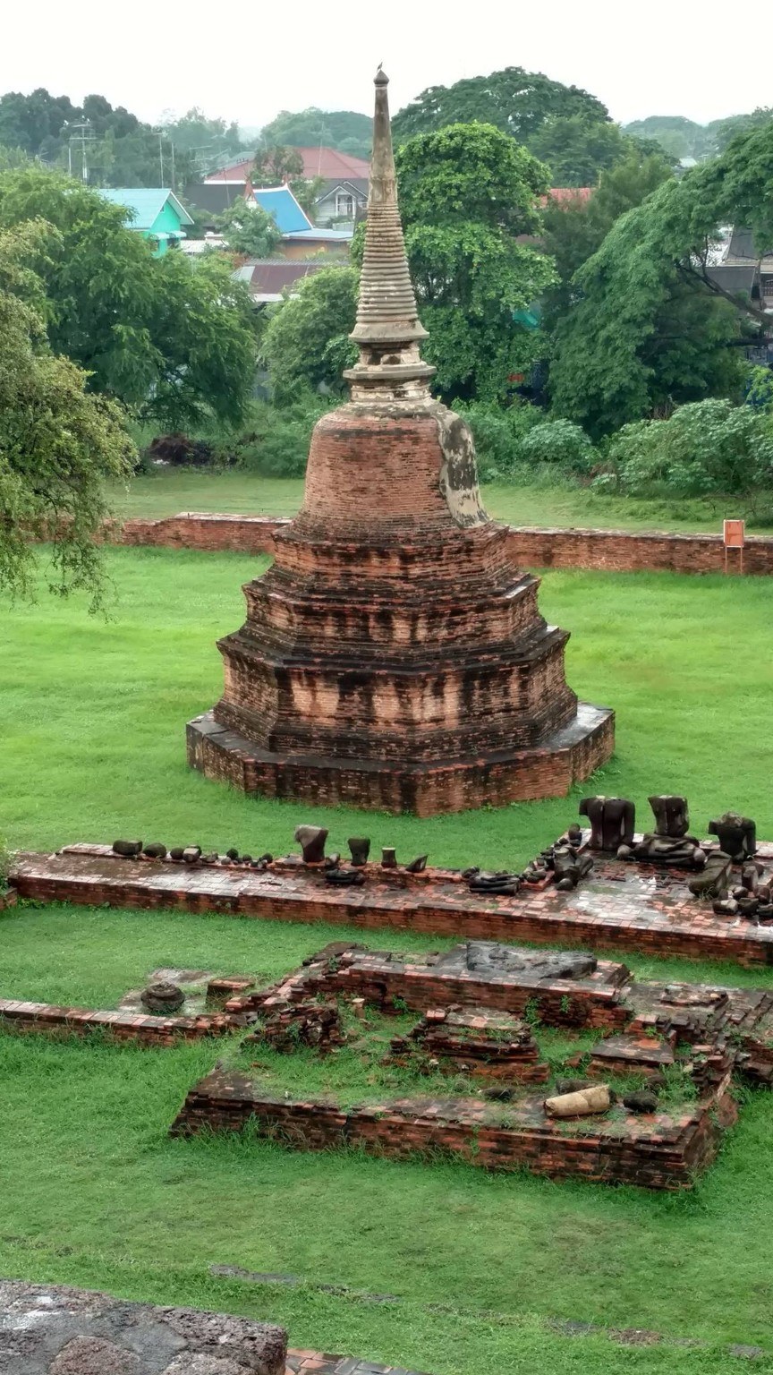 A stupa and temple foundations surrounded by bright green grass at Ayutthaya