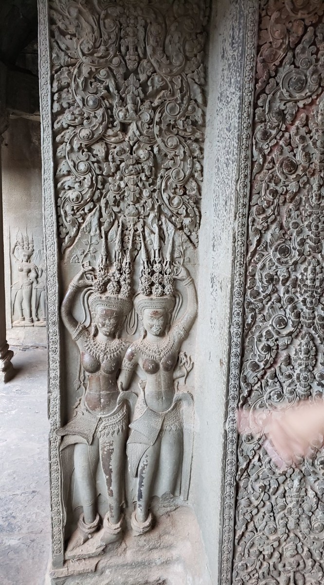 Detailed sandstone bas-relief carvings at Angkor Wat showing apsaras and floral motifs