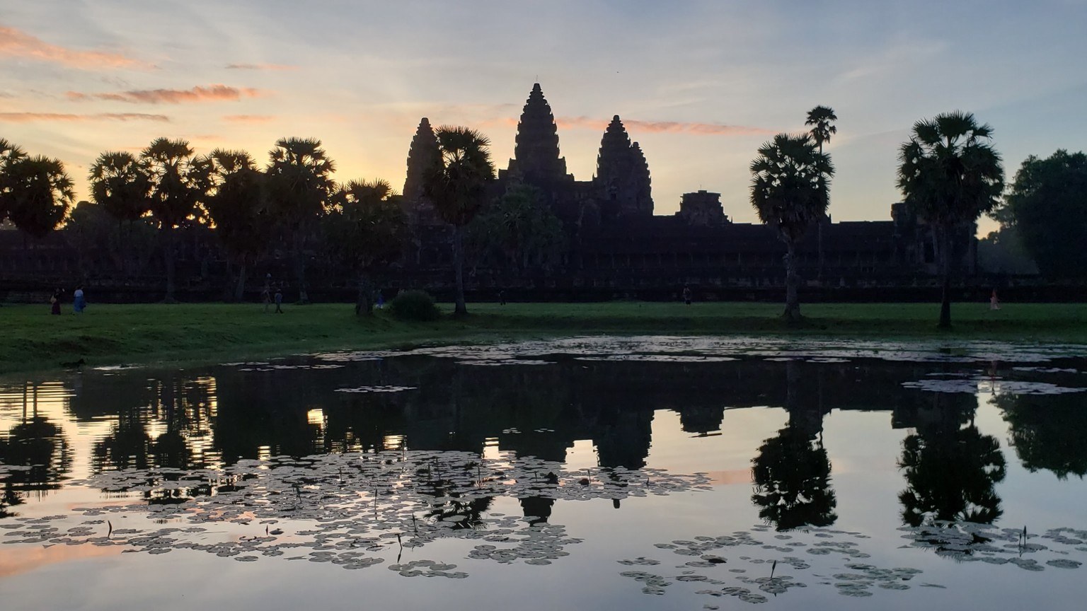 Angkor Wat silhouetted before dawn, with the first hints of pink light behind the towers