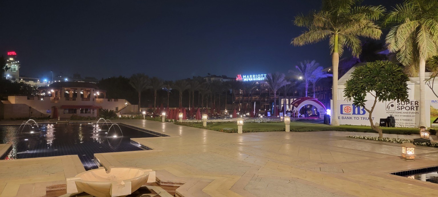 Mena House courtyard lit warmly at night with the Great Pyramid faintly visible behind