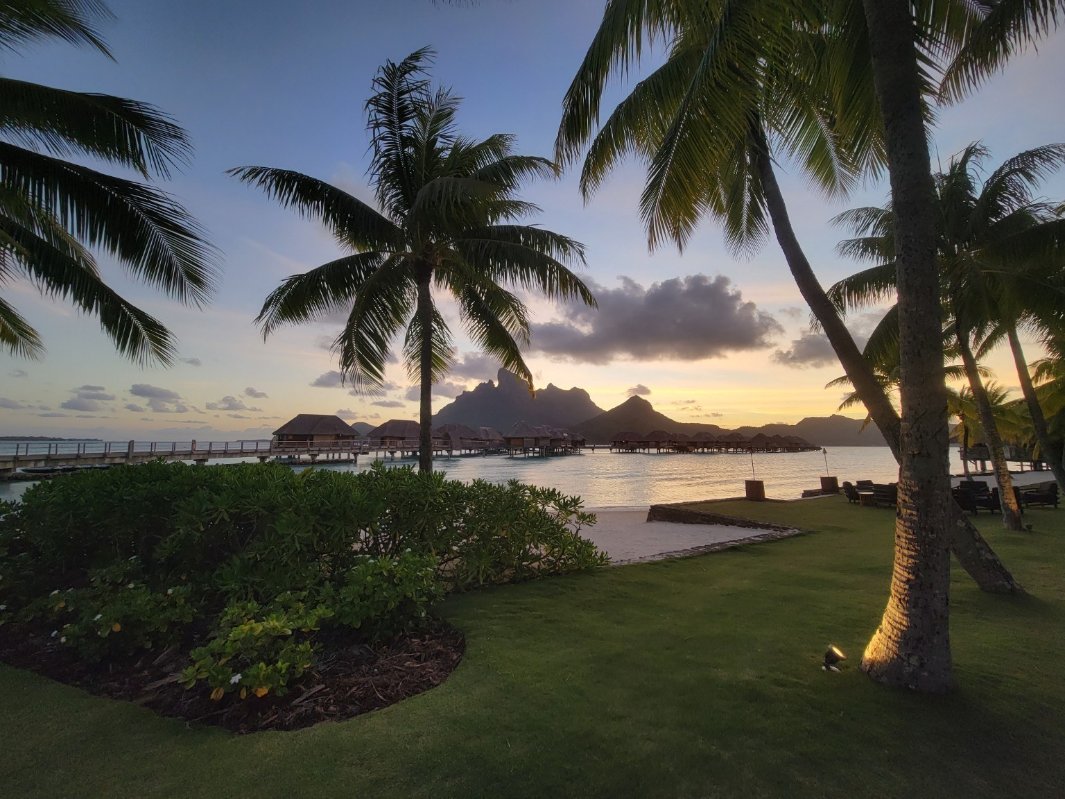 Sunset over the Bora Bora lagoon framed by palm trees