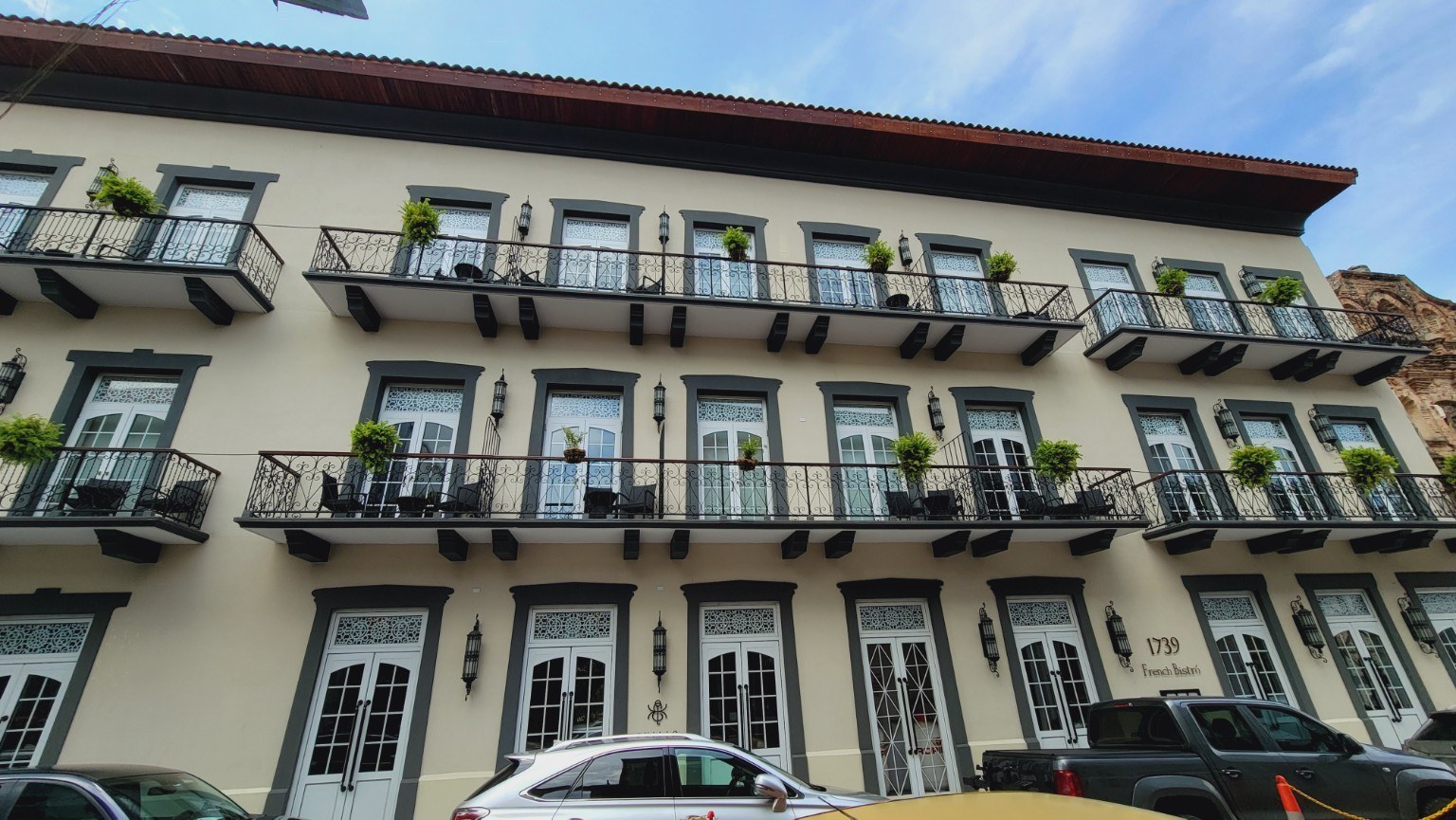 Restored Casco Viejo facade with cream walls, iron balconies, and hanging plants
