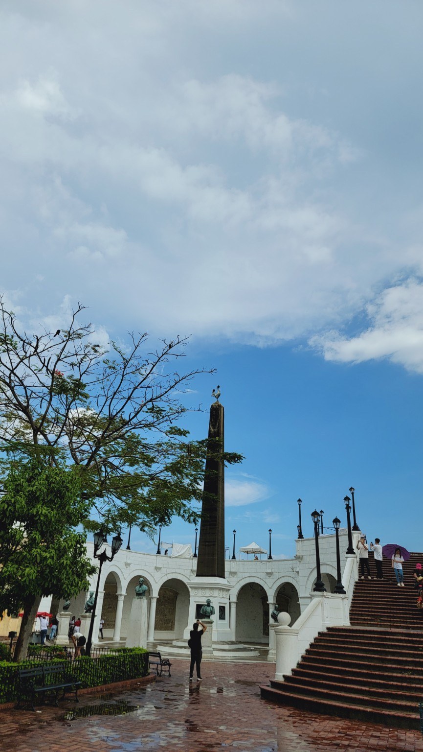 Plaza de Francia obelisk topped by a rooster, with white arcade and staircase in Casco Viejo