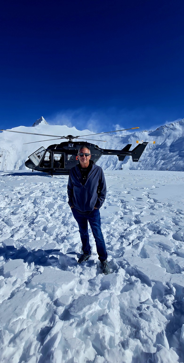 Scott Barlow beside a helicopter on a snow landing in the Southern Alps