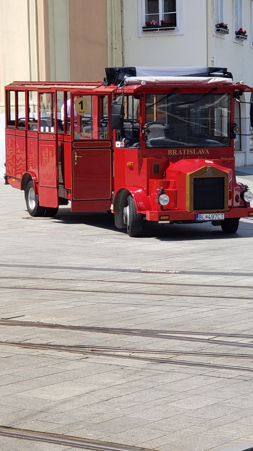 A bright red sightseeing trolley parked in central Bratislava