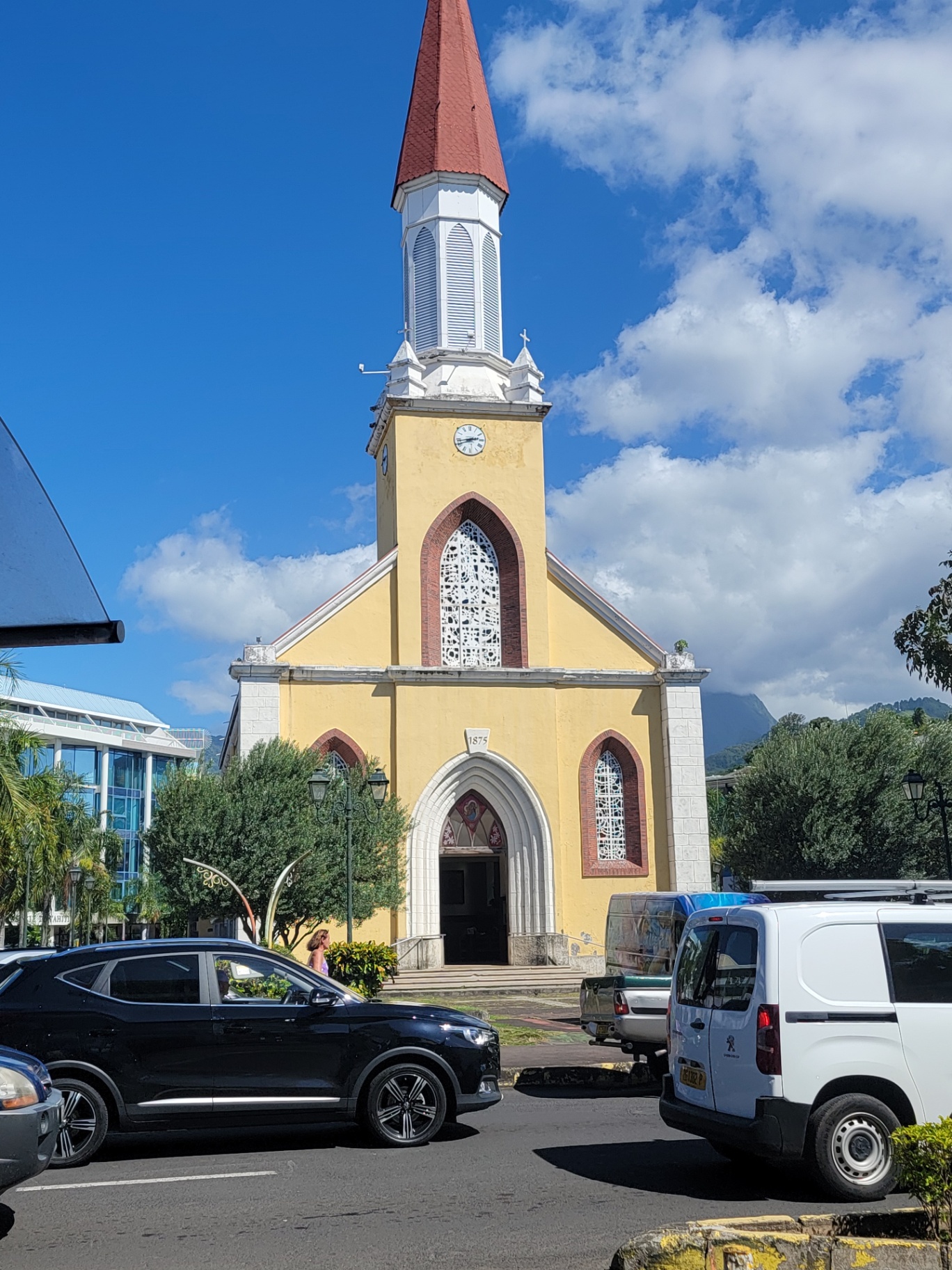 Yellow Cathédrale Notre-Dame de Papeete with its red steeple against a blue sky