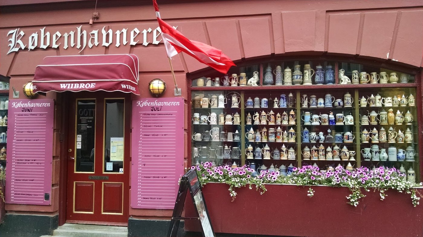 A Copenhagen pub front packed with steins, flowers and a Danish flag