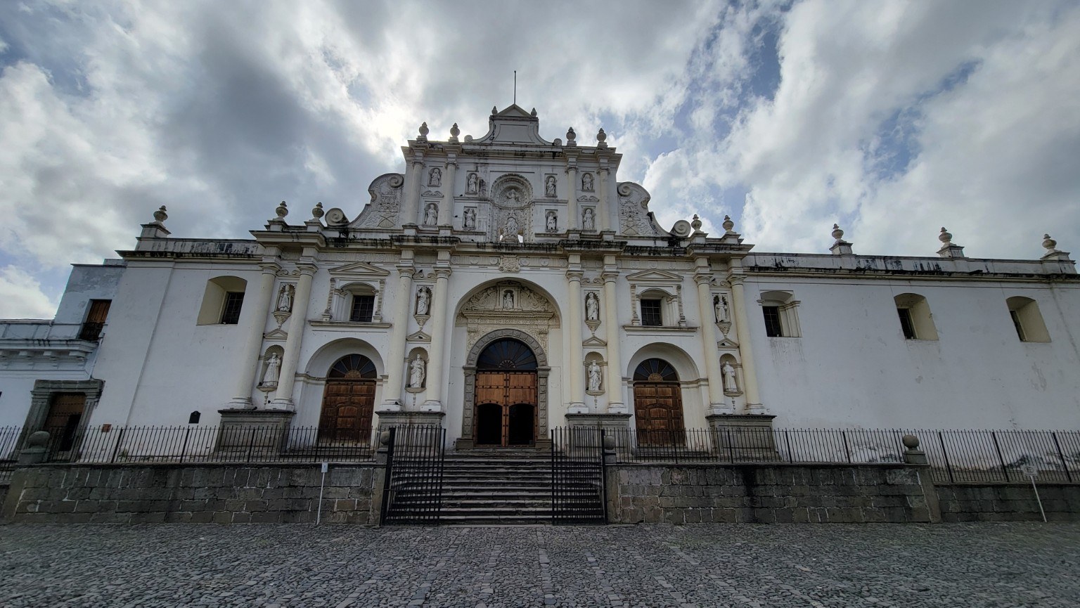 Whitewashed Catedral de Santiago facade in Antigua under dramatic clouds