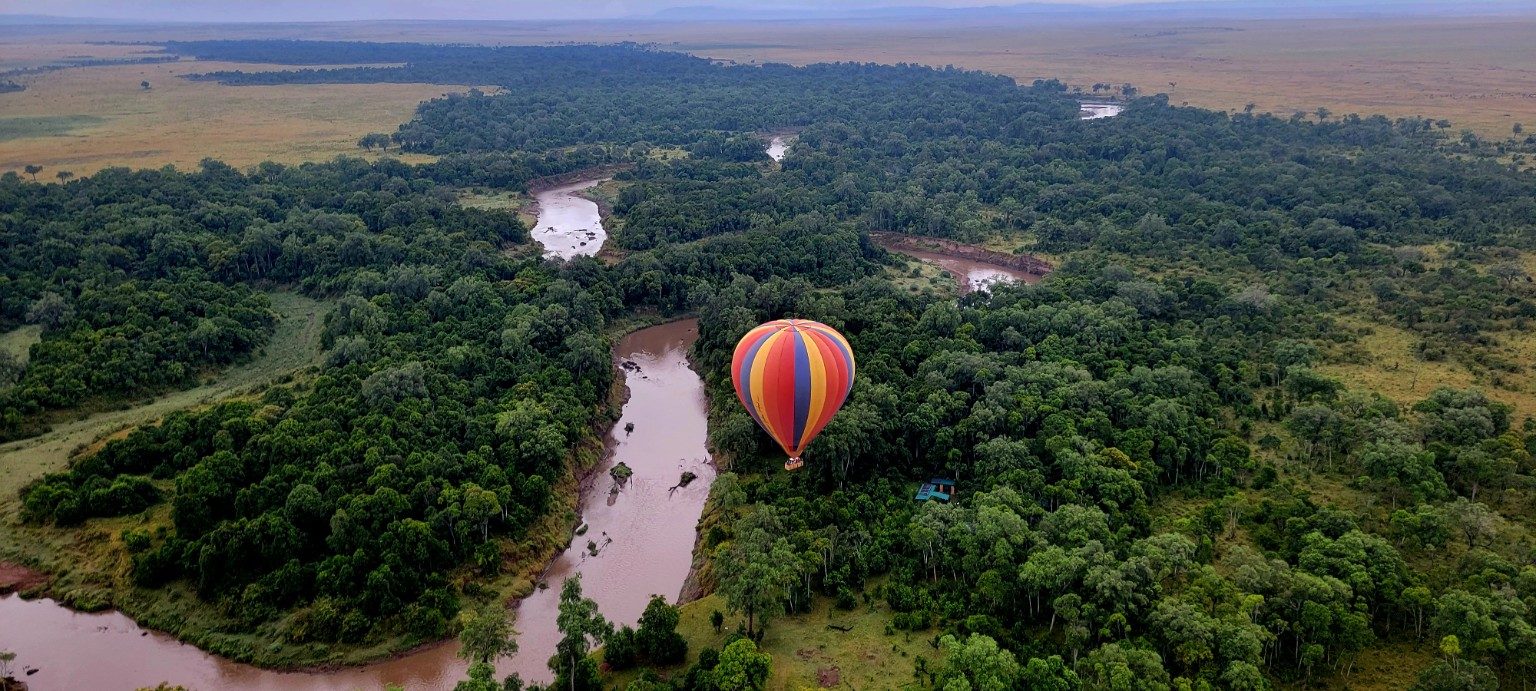Aerial view from a hot-air balloon over the Mara River and forest corridors at sunrise