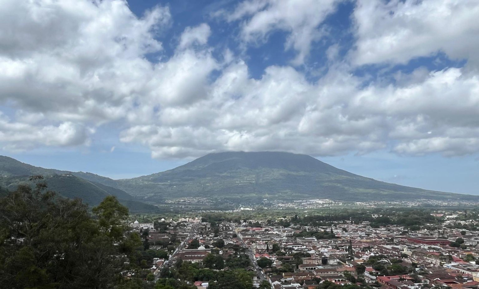 Aerial-style view of Antigua's red-tiled rooftops with Volcán de Agua looming behind