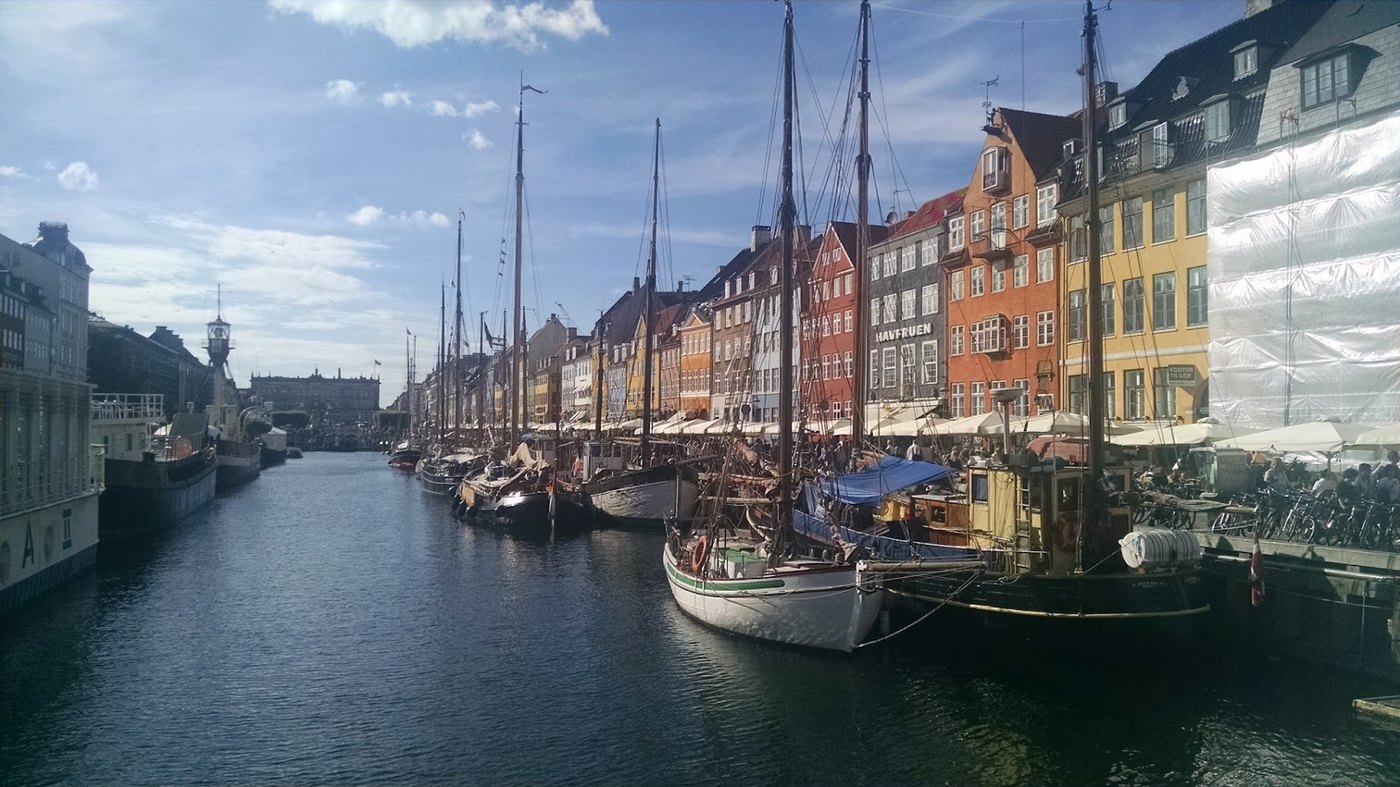 Classic wooden canal boats lined up below the painted townhouses of Nyhavn