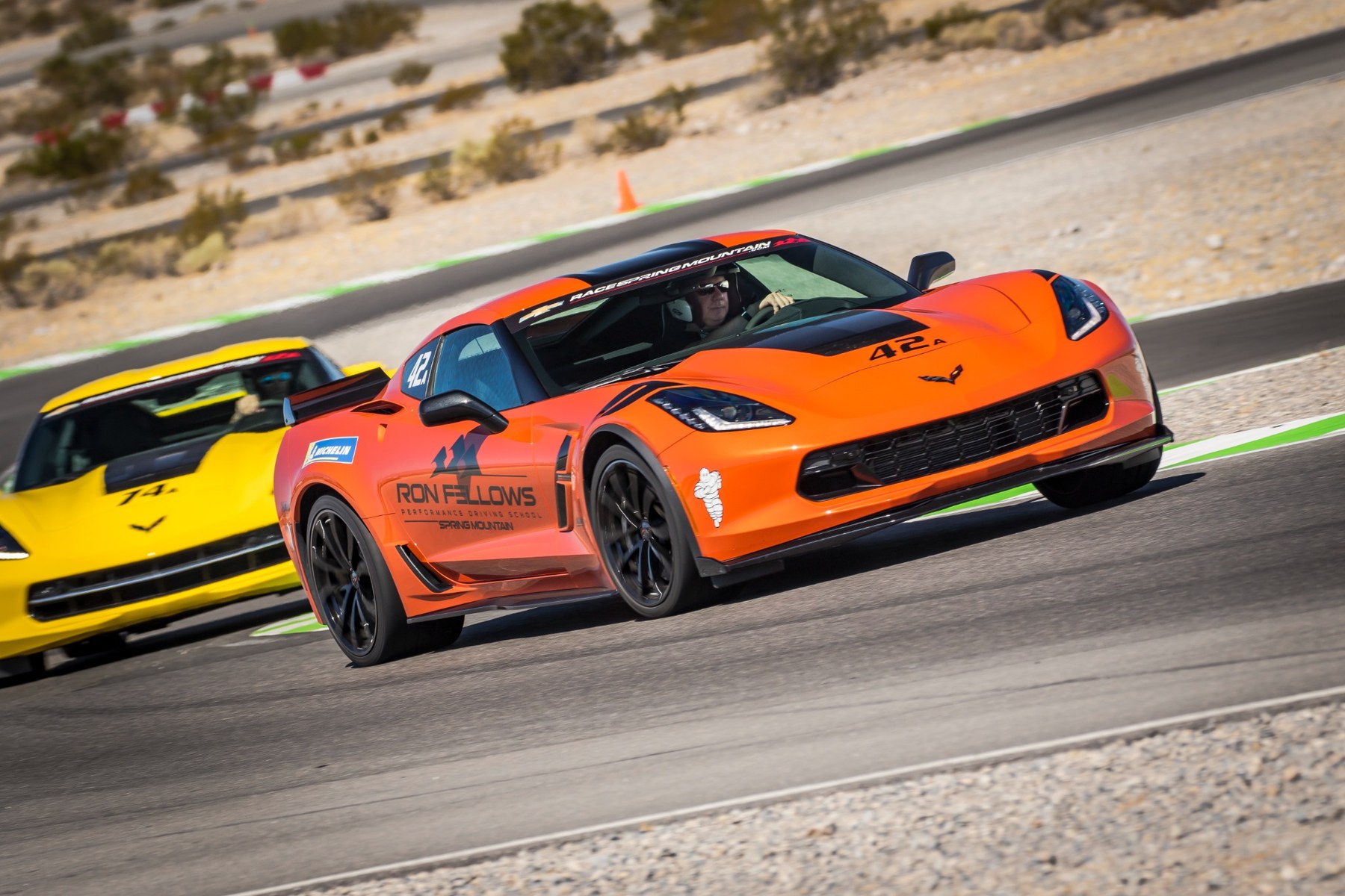 Orange Corvette leading a yellow Corvette on track