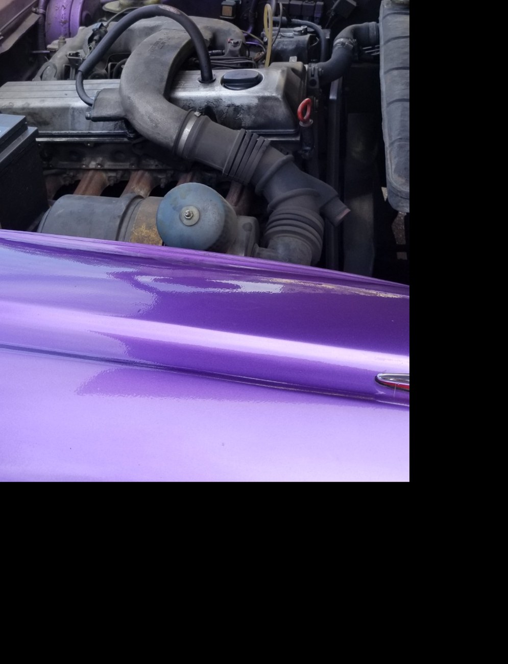 Open hood of a purple vintage car in Havana showing a non-original swapped engine