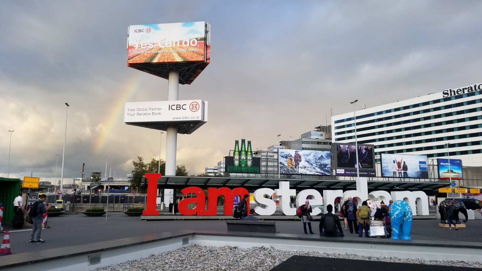 I amsterdam sign with rainbow and cloudy sky