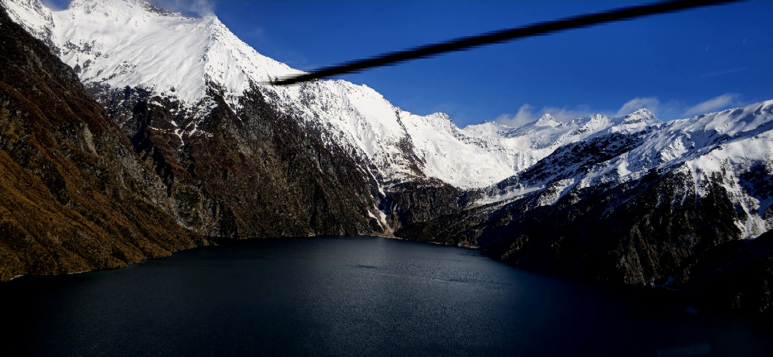 Dark alpine lake beneath snow-covered mountains