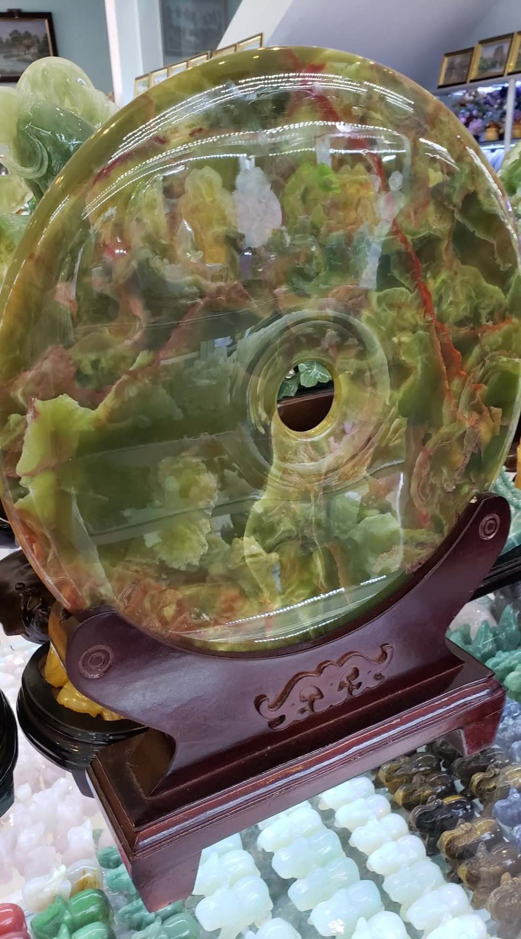 Large polished green jade disc on a wooden stand in a Da Nang workshop
