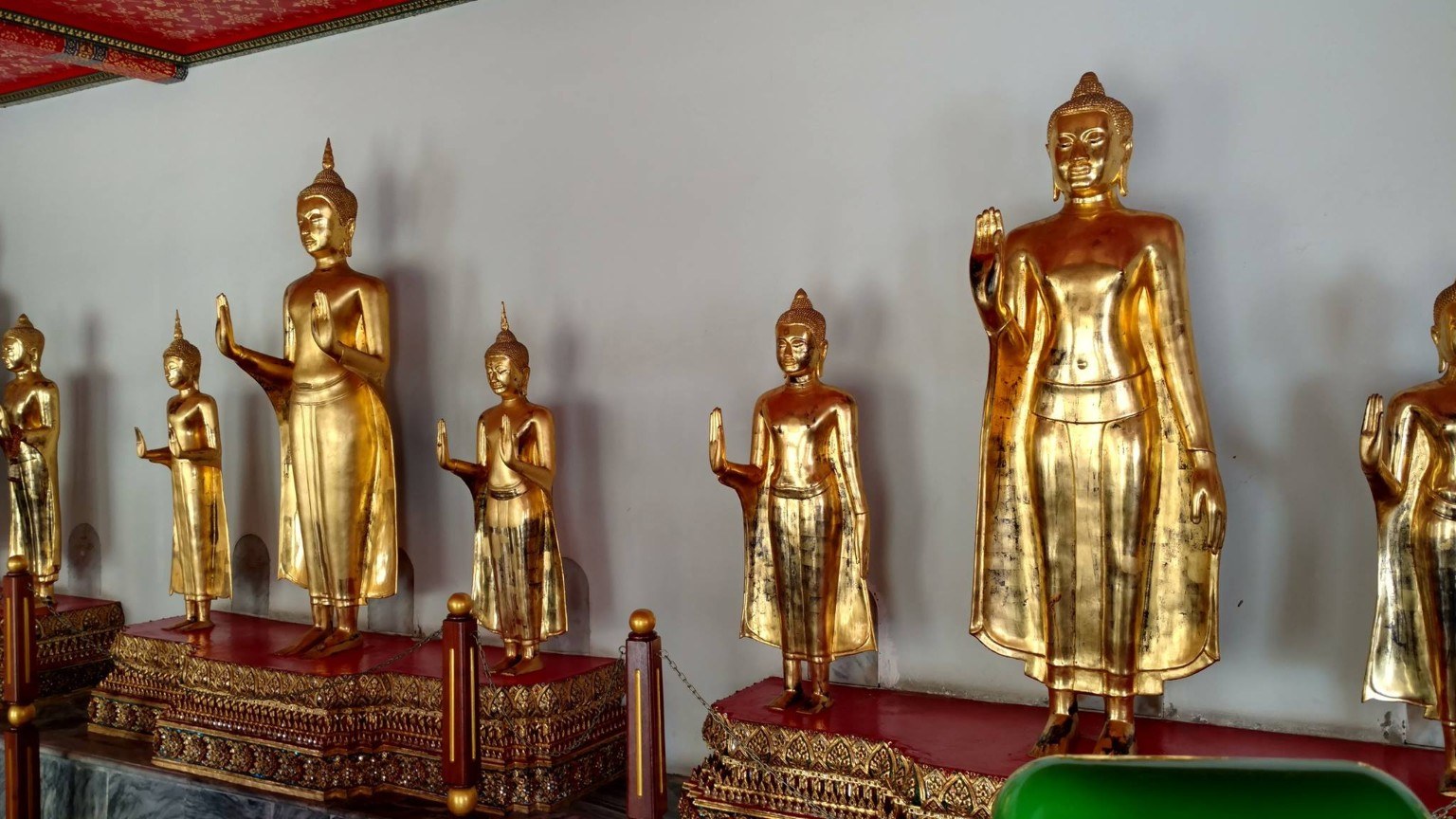 Golden standing Buddha figures aligned along a temple wall at Wat Pho