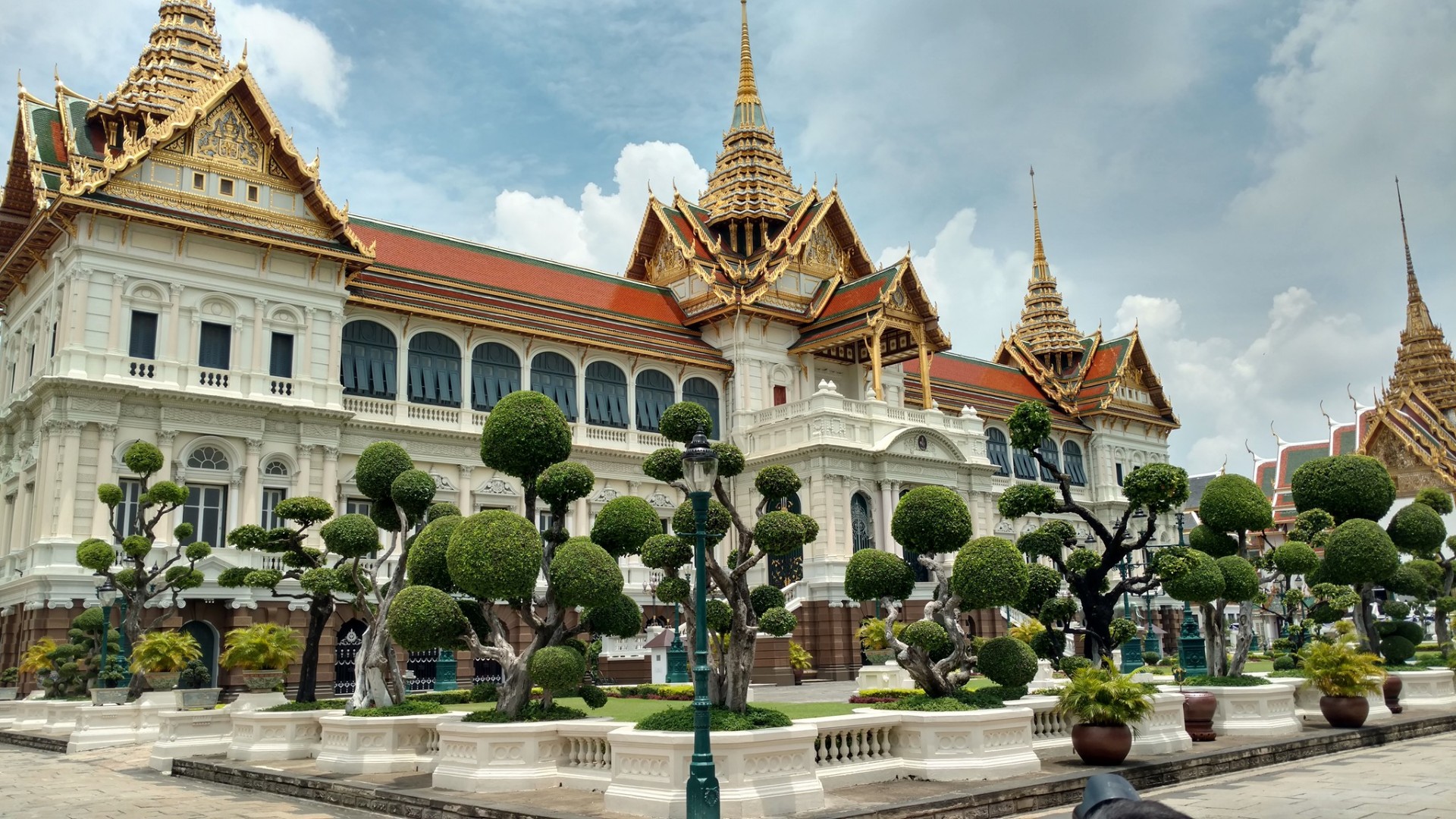 The Chakri Maha Prasat Hall at Bangkok's Grand Palace with manicured topiary trees in front
