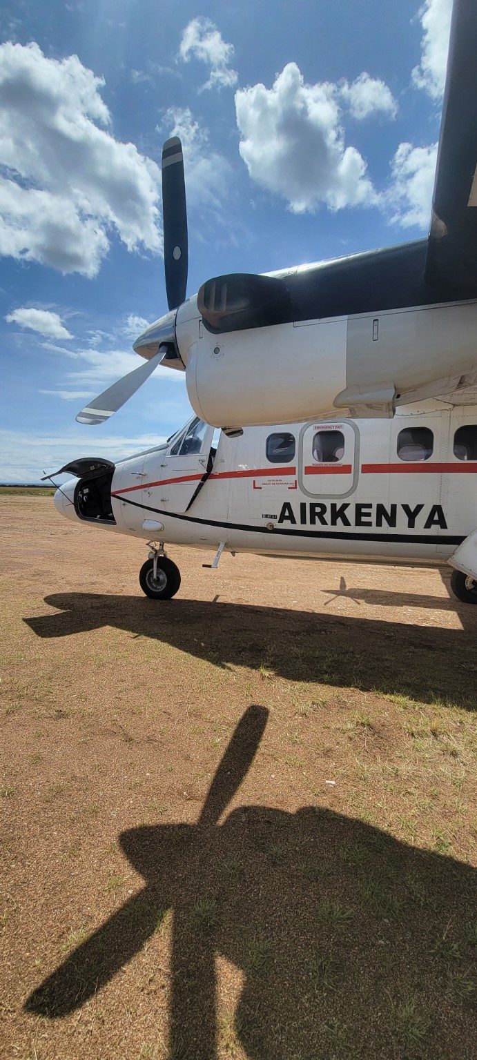 Small AirKenya turboprop parked on a dirt strip in the Mara