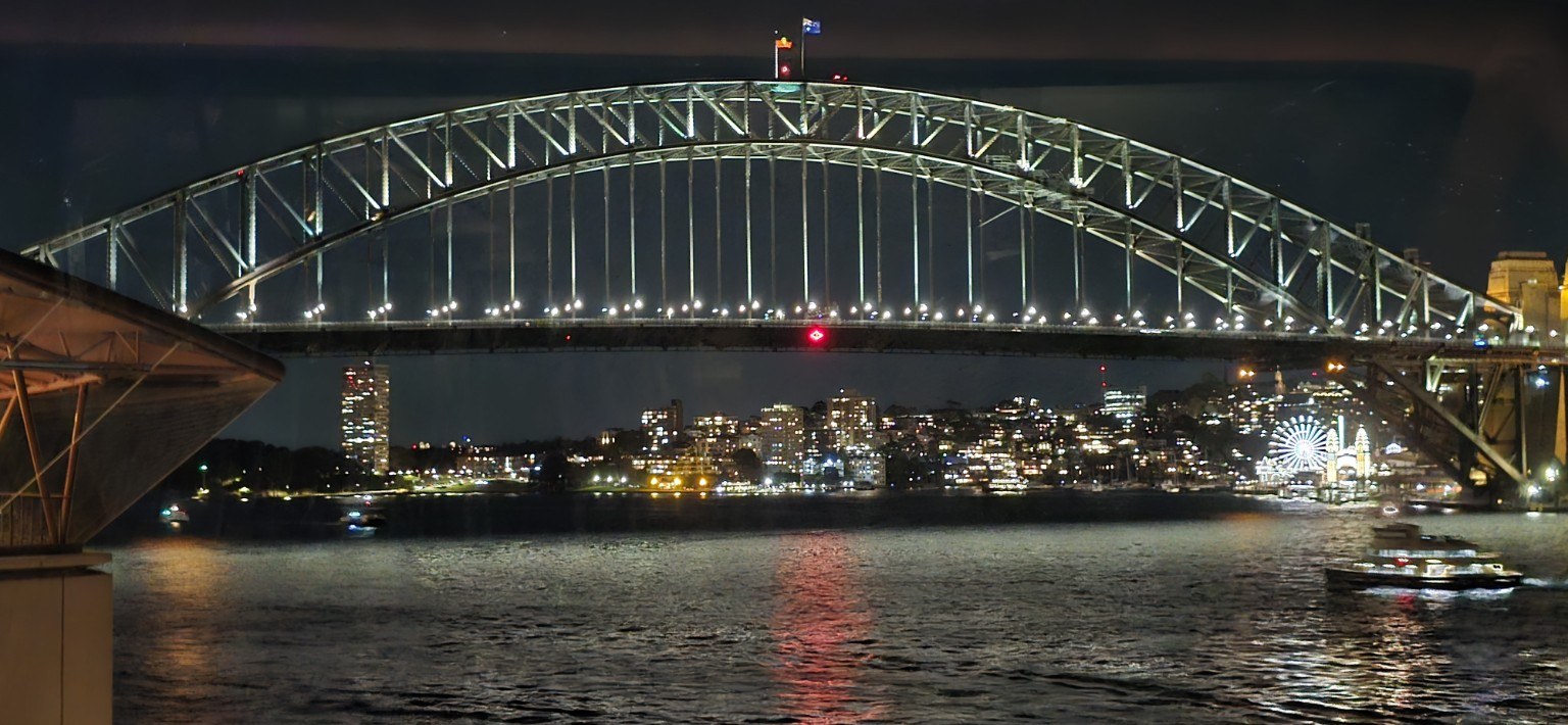 Sydney Harbour Bridge lit up at night with reflections in the water