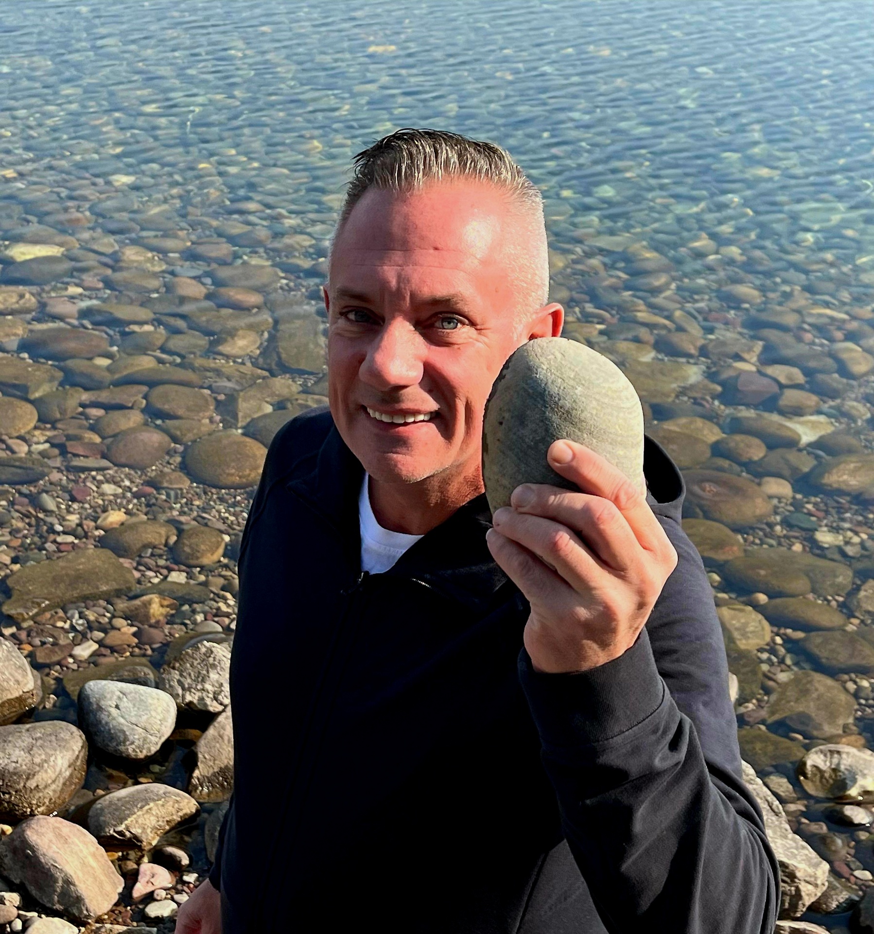 Scott holding a rock at the water's edge