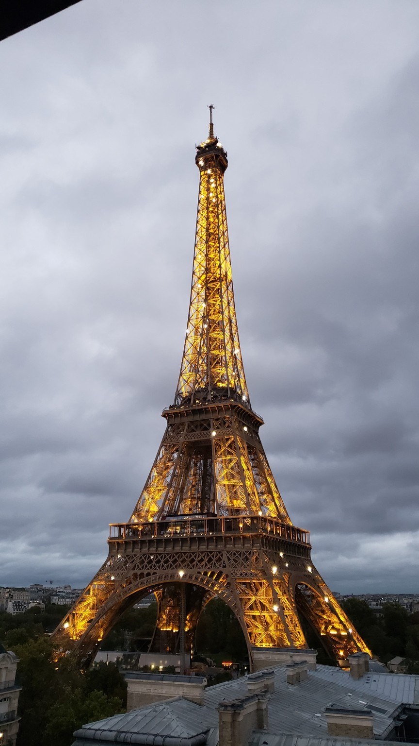 The Eiffel Tower glowing against a stormy Paris sky