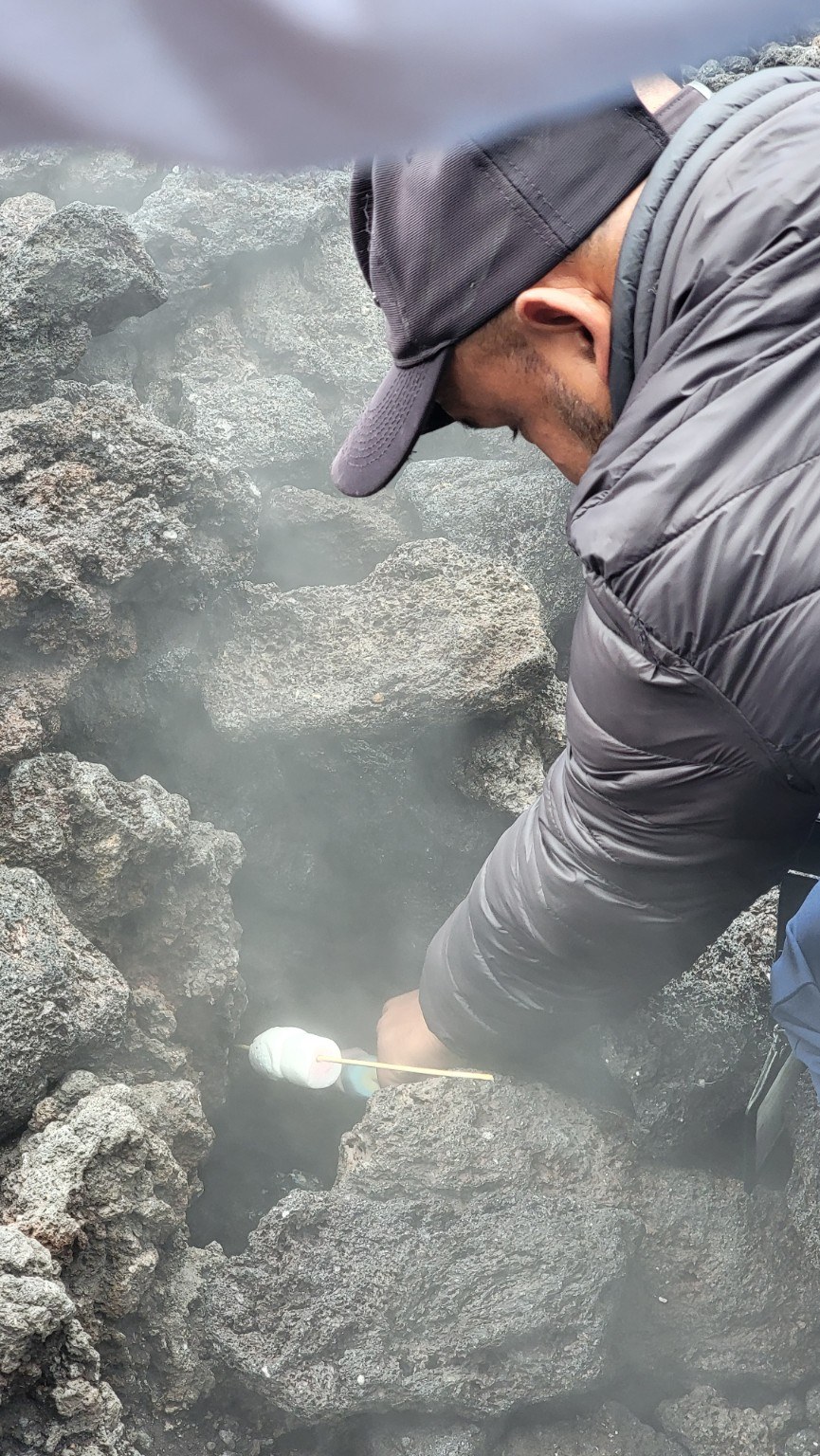 Pacaya guide roasting a marshmallow over steam rising from volcanic rocks