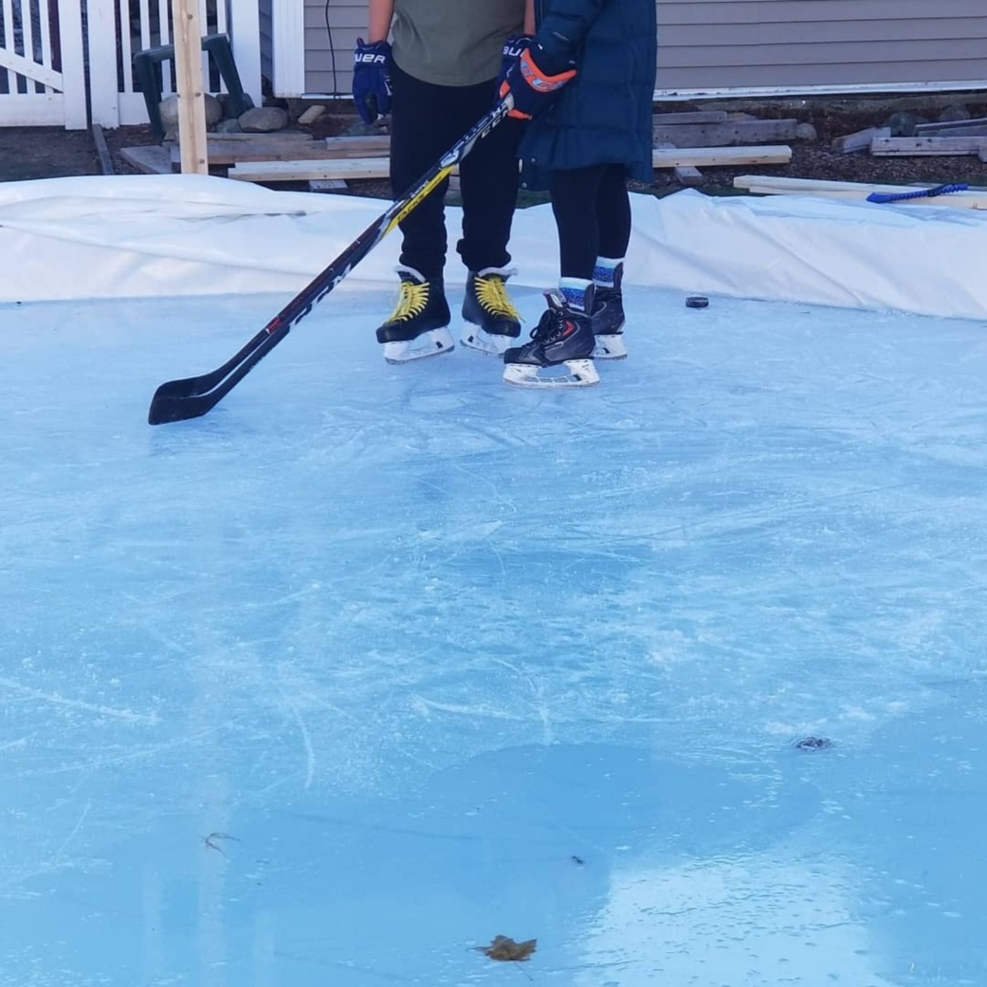 Close up of kids skates and a puck on backyard ice