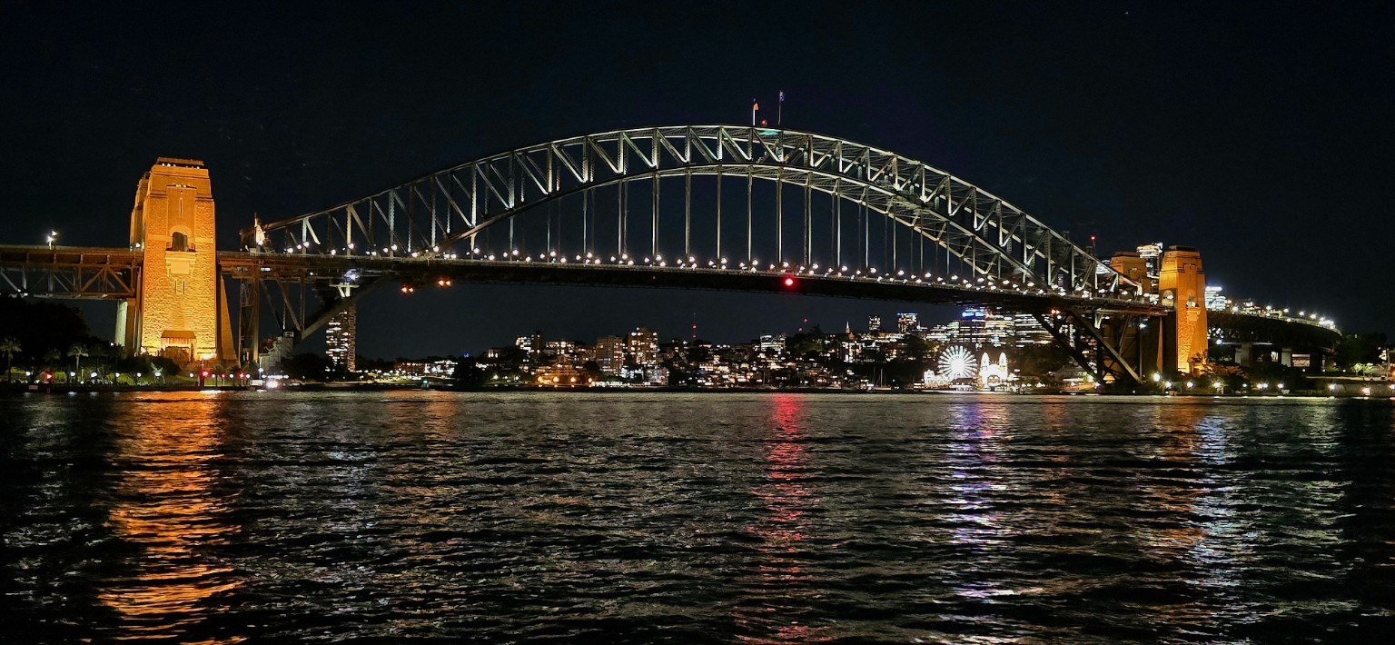 Sydney Harbour Bridge silhouetted at sunset over the water