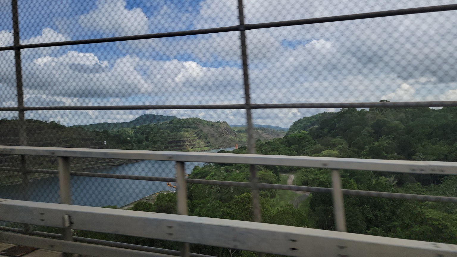 View through a bridge railing of the Panama Canal cut and surrounding rainforest
