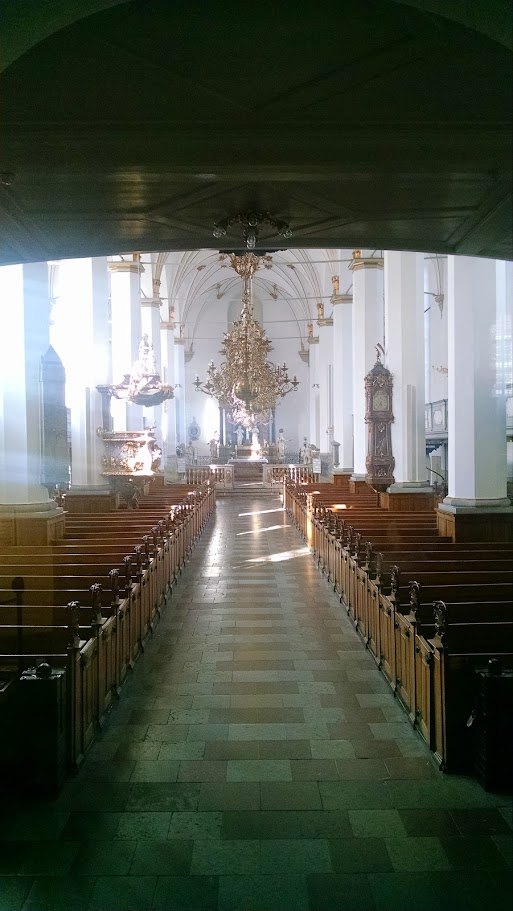 A quiet church interior, all white walls, long nave, wood pews and old-world restraint