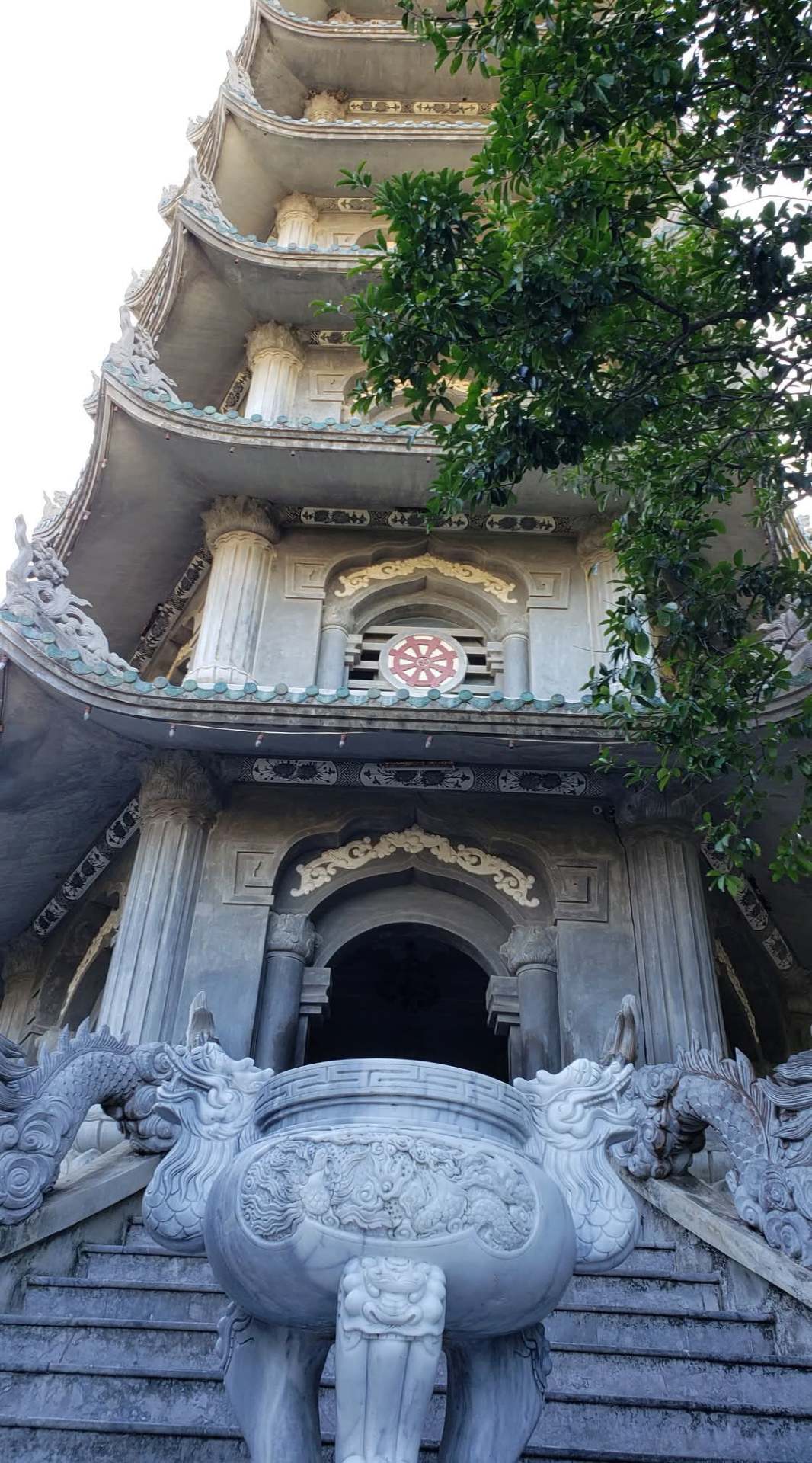 Tall multi-tiered pagoda at the Marble Mountains with carved stone dragons in the foreground