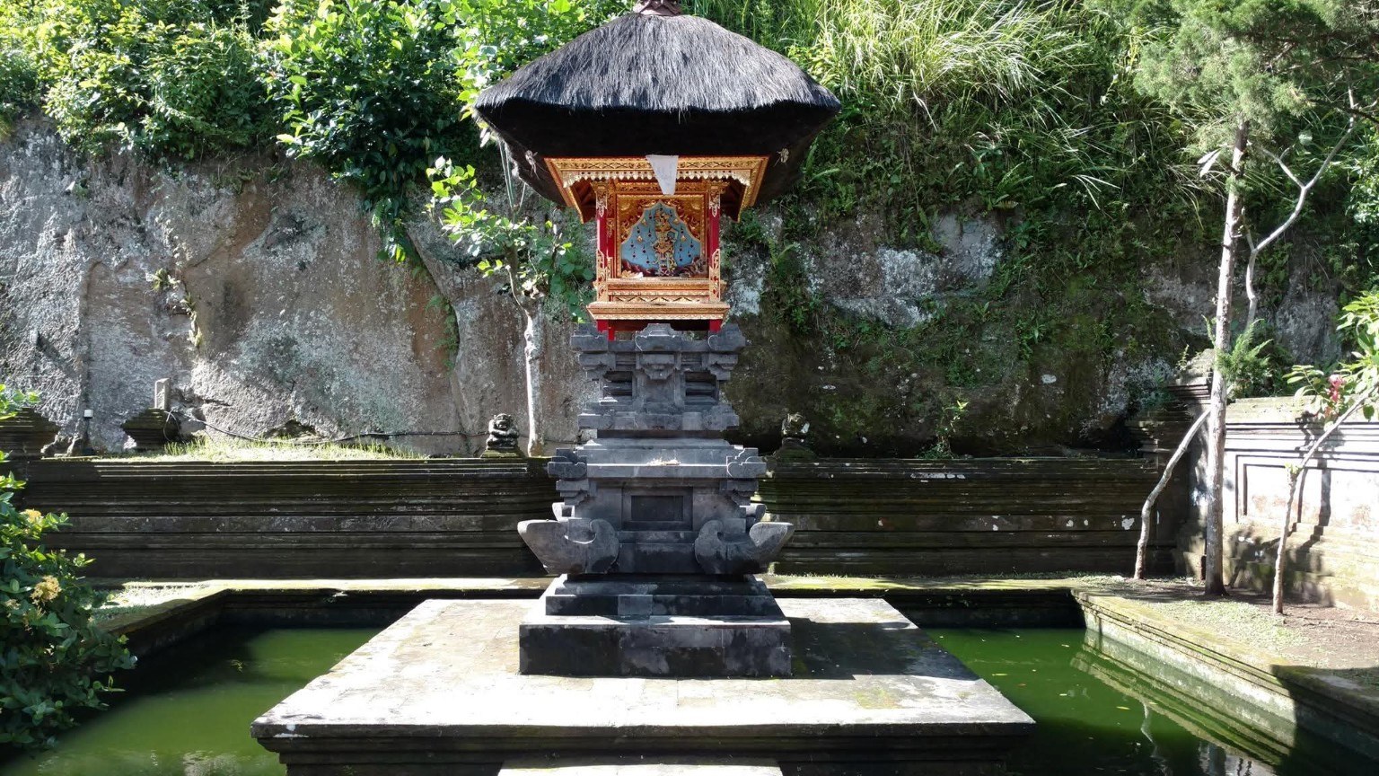 A quiet temple structure set over water and surrounded by greenery