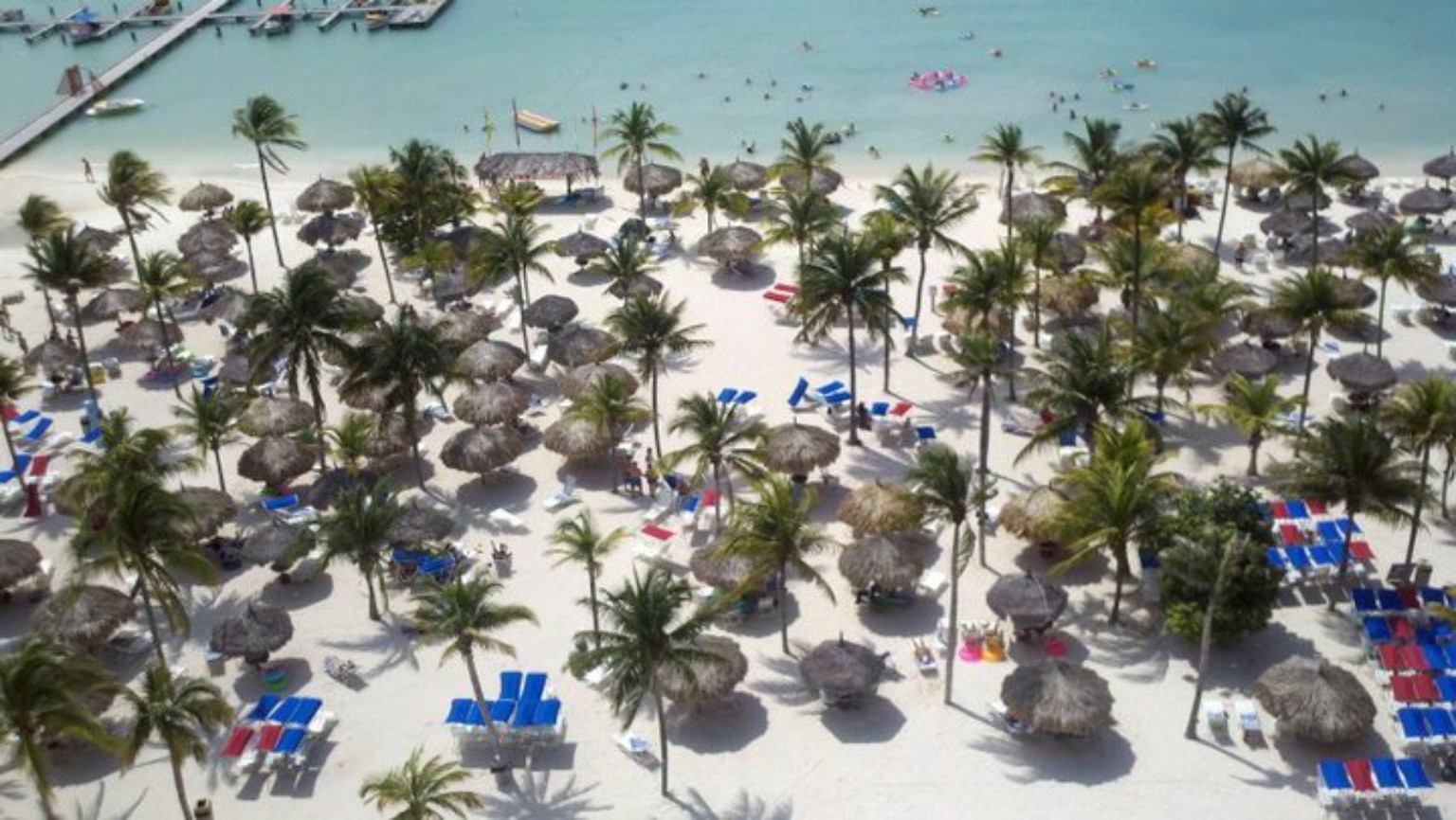 Palm shadows and palapas on an Aruban beach