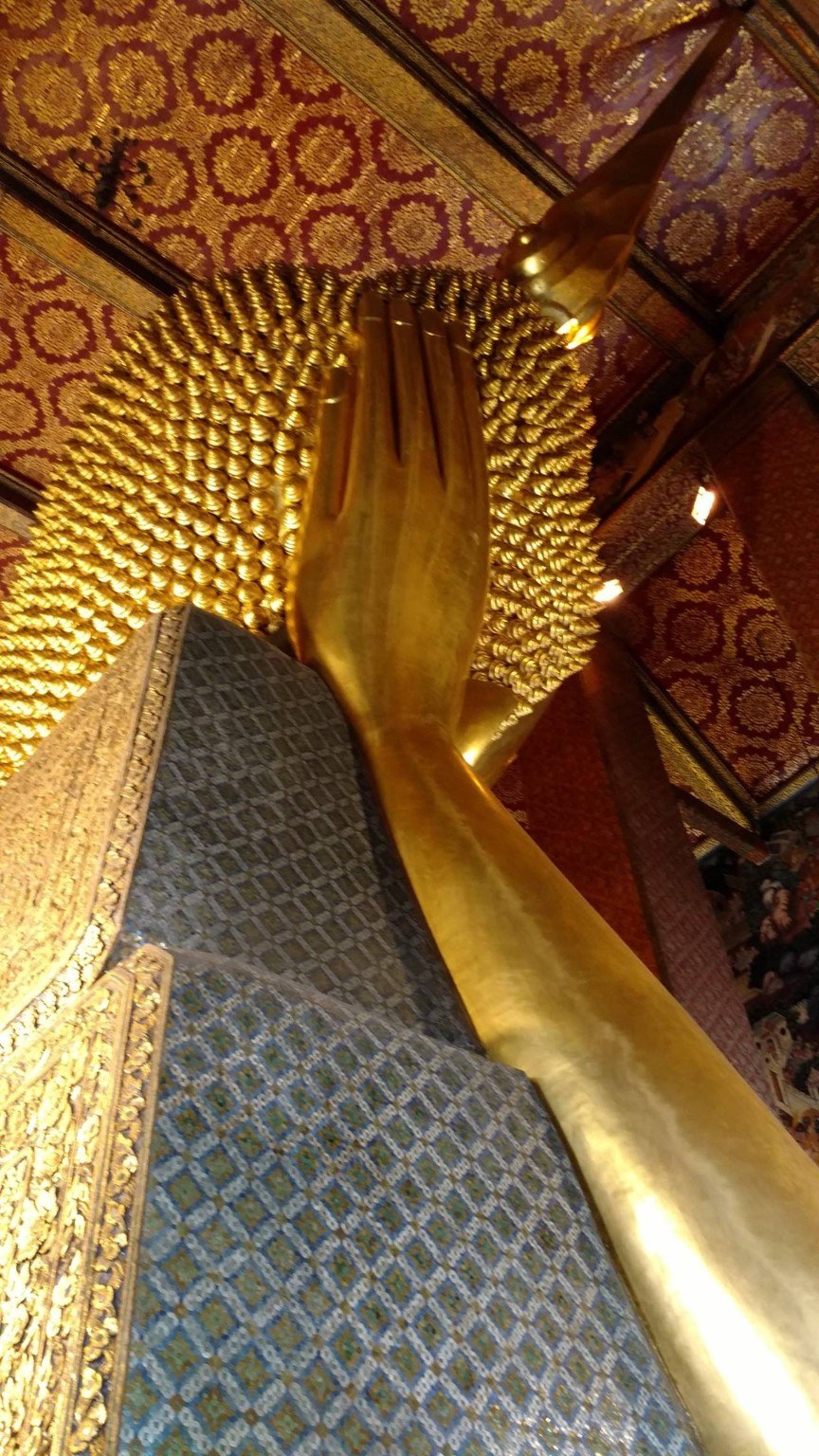 A traveler standing next to the Reclining Buddha for scale