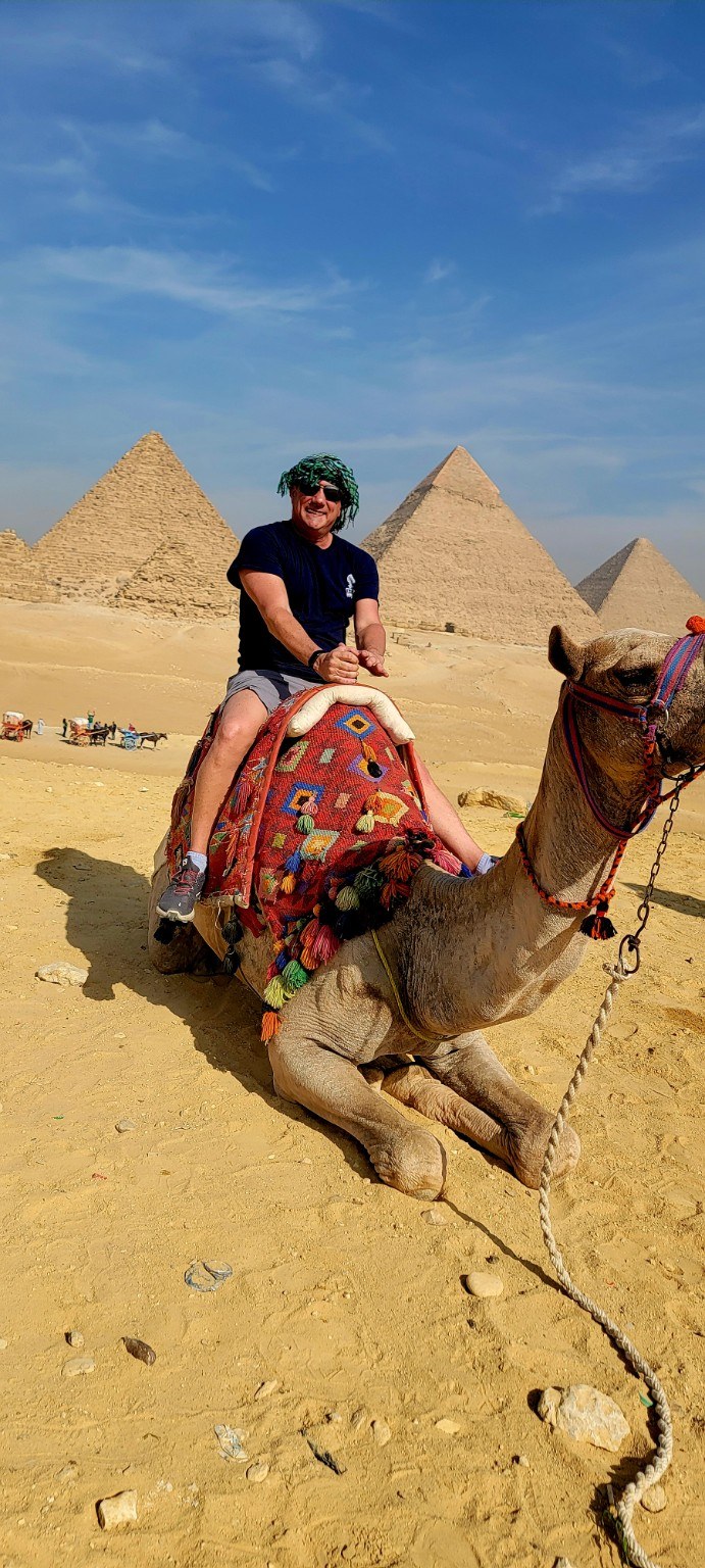 Traveler on a camel in the Giza desert with the pyramids layered behind